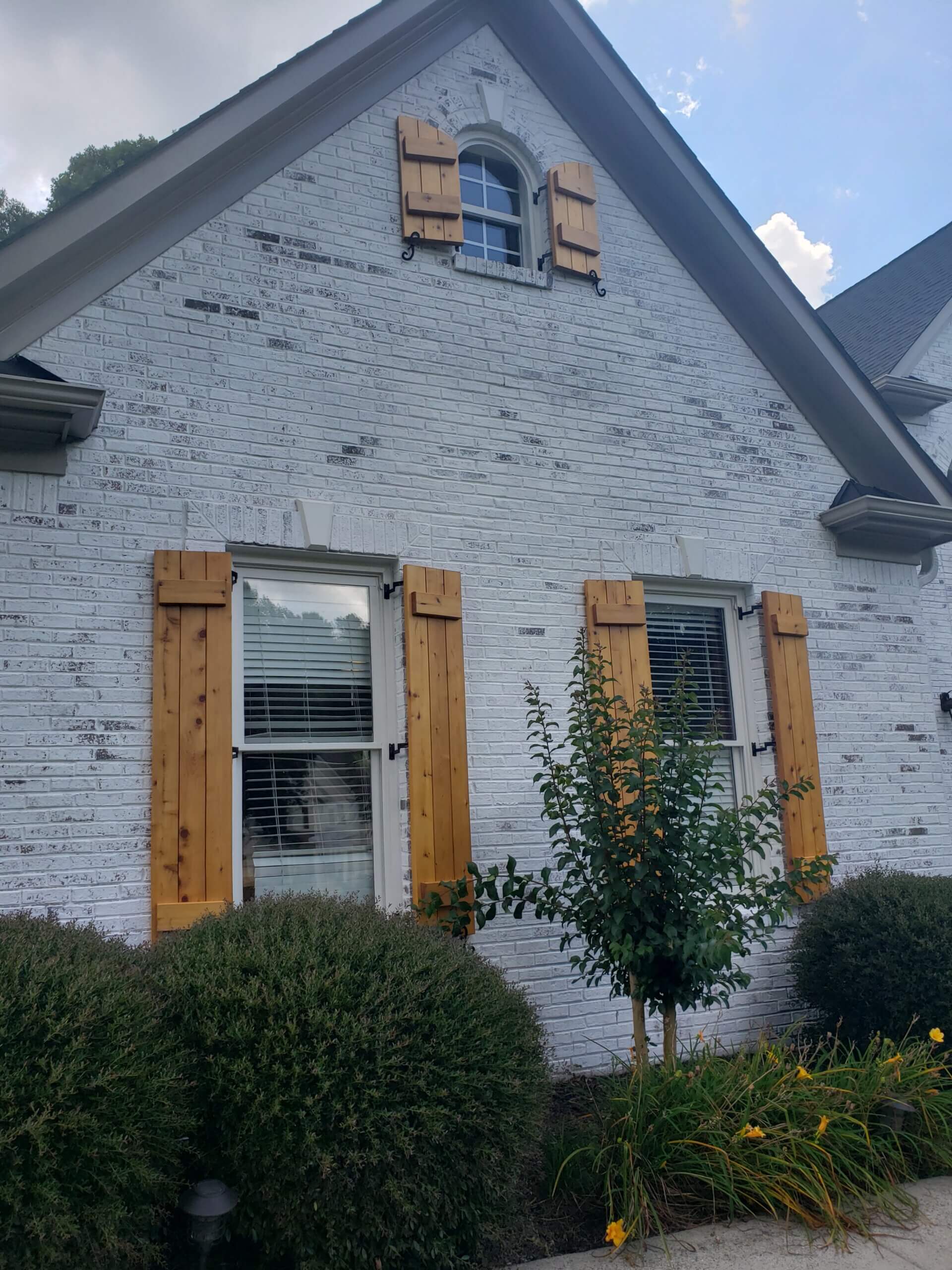 Grey brick house with wooden shutters and arched windows