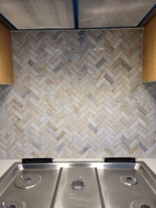 Stone subway tile in blue grey and earth tones laid in a herringbone pattern