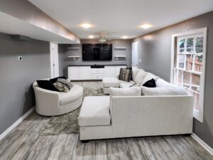 Finished basement with new walls, flooring installed, and paint staged with neutral furniture